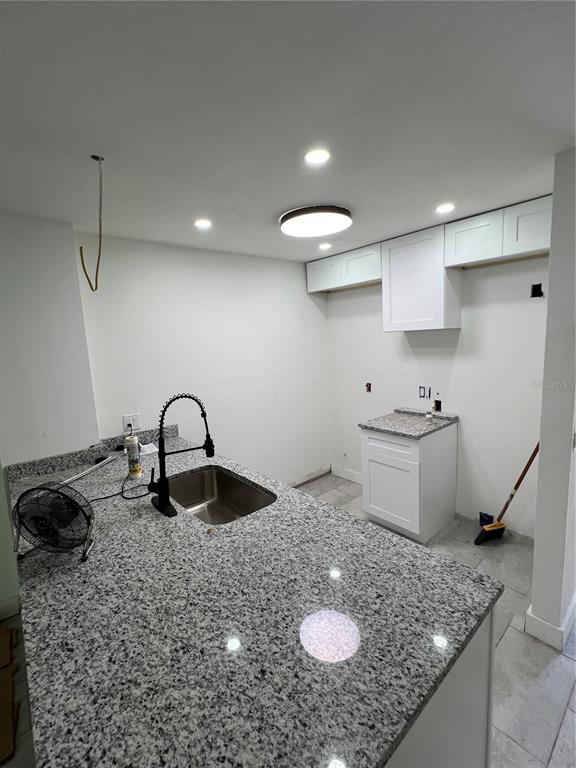 A kitchen under renovation features white cabinets, granite countertops, and a stainless steel sink — 6138 OAK CLUSTER CIRCLE, TAMPA, FL