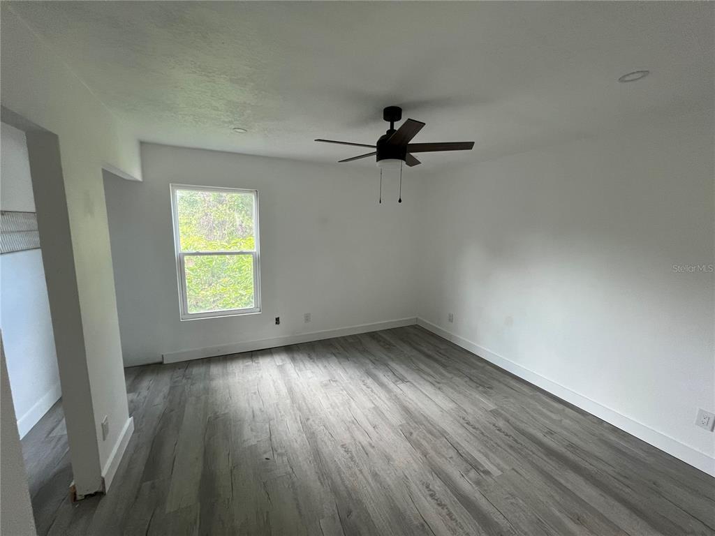 An empty bedroom features white walls, gray wood-look flooring, and a ceiling fan — 6138 OAK CLUSTER CIRCLE, TAMPA, FL