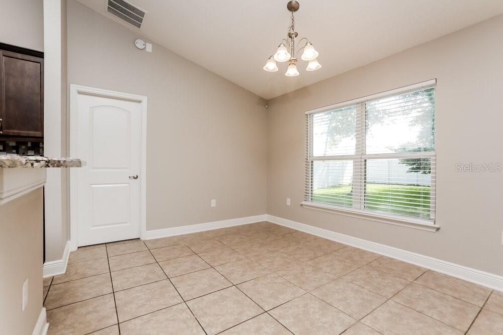 A dining area with beige walls, tile flooring, a chandelier, and a large window — 2214 ANGEL FISH LOOP, LEESBURG, FL
