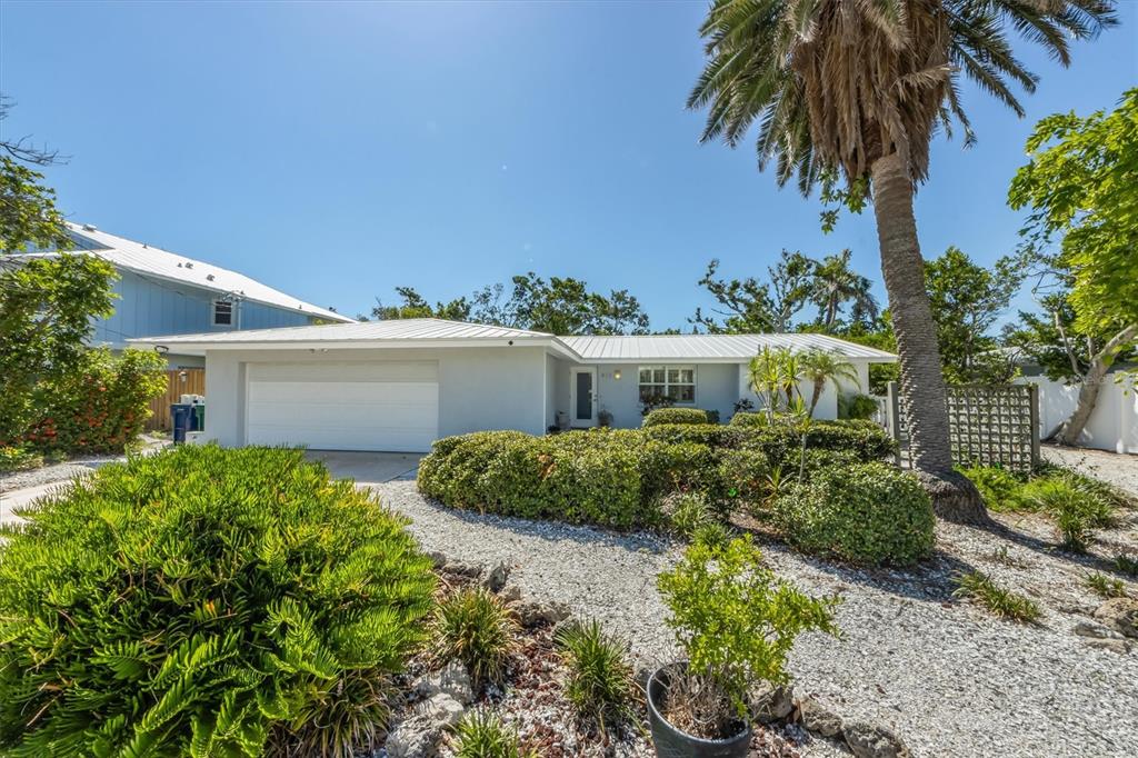 A single-story house with a white metal roof, garage, and landscaped front yard — 413 POINSETTIA ROAD, ANNA MARIA, FL