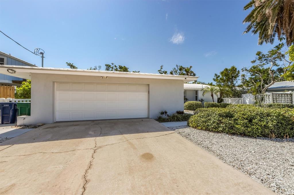 A concrete driveway leads to a single-story house with a white two-car garage door — 413 POINSETTIA ROAD, ANNA MARIA, FL