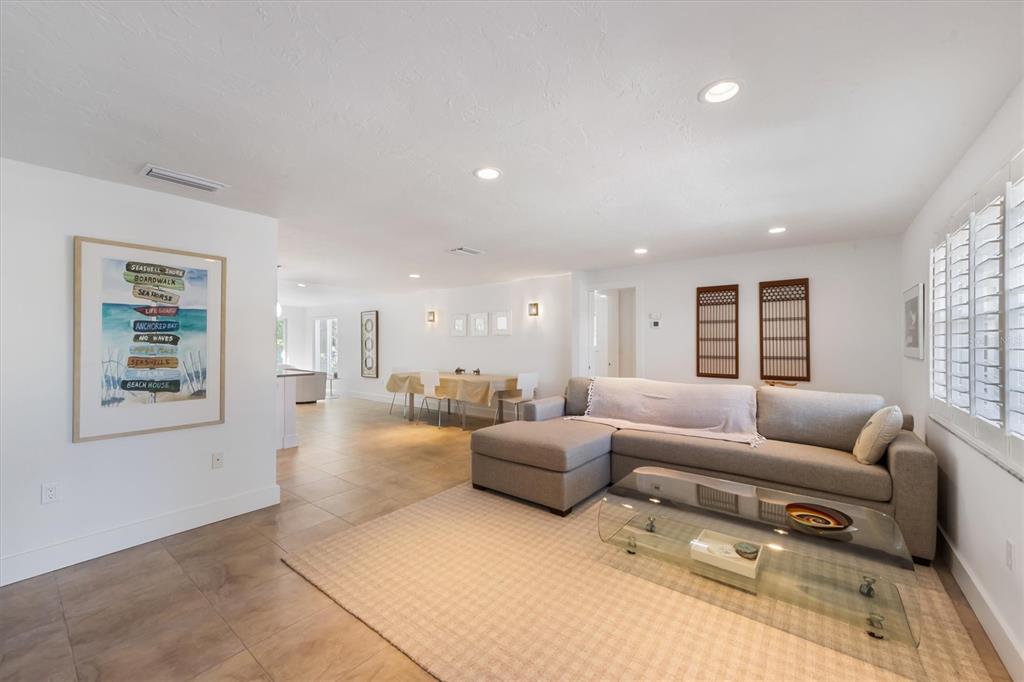 A living room features a gray sectional sofa, glass coffee table, and tiled flooring — 413 POINSETTIA ROAD, ANNA MARIA, FL