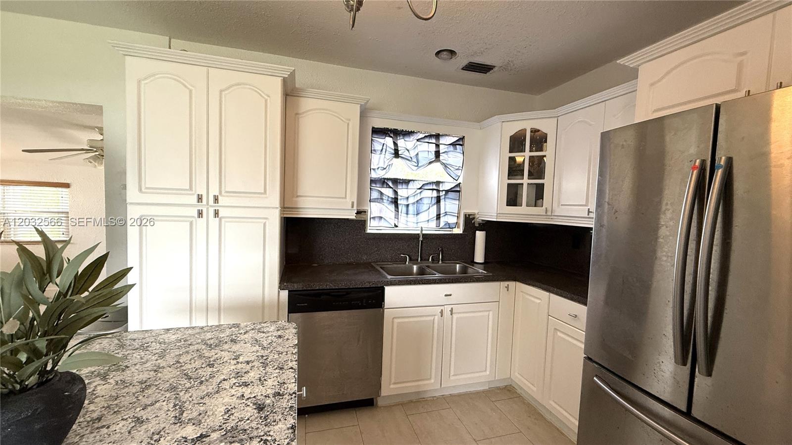 A kitchen features white cabinets, dark countertops, stainless steel appliances, and a granite-topped island — 1245 NE 203rd St, Miami FL 33179, MIAMI, FL