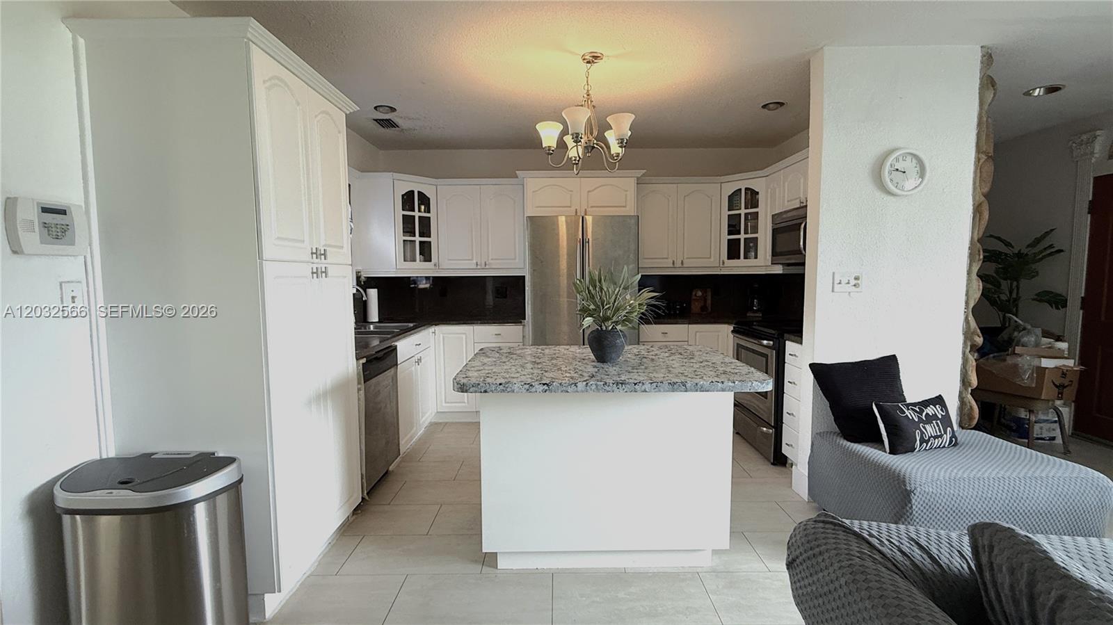 A kitchen features white cabinets, granite countertops, a central island, and stainless steel appliances — 1245 NE 203rd St, Miami FL 33179, MIAMI, FL
