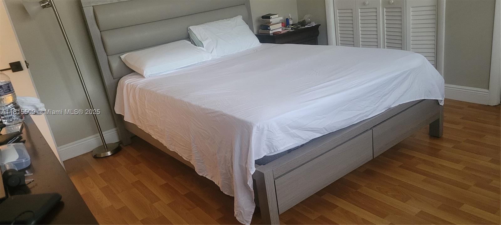 A bedroom features a gray upholstered headboard, a bed with white linens, and wood flooring — 1958 Monroe St # 107, Hollywood FL 33020, HOLLYWOOD, FL