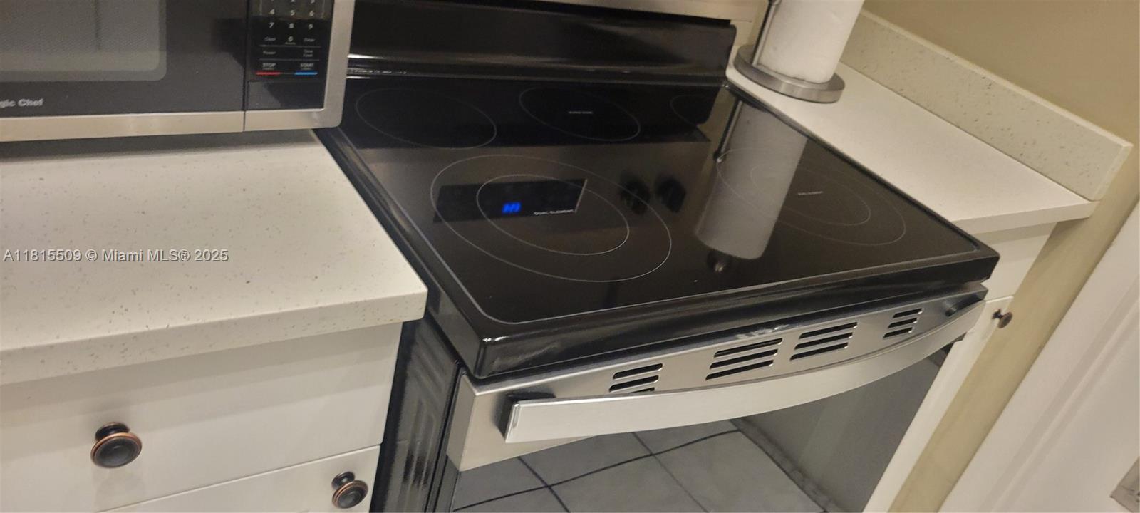 A stainless steel electric range with a glass cooktop sits next to a white cabinet — 1958 Monroe St # 107, Hollywood FL 33020, HOLLYWOOD, FL