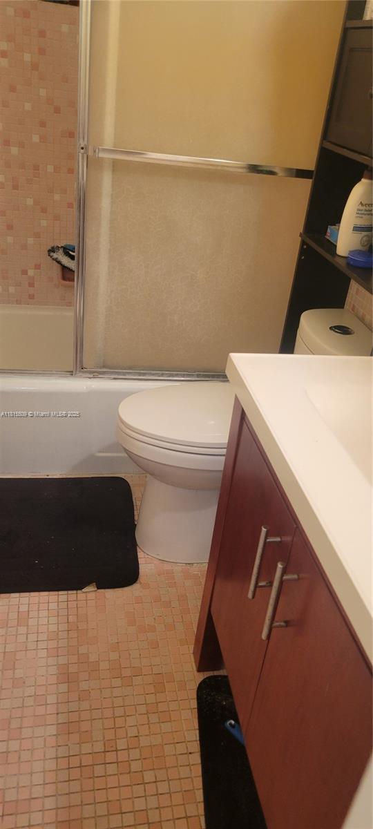 A bathroom features a white toilet, a vanity with a dark cabinet, and a shower stall — 1958 Monroe St # 107, Hollywood FL 33020, HOLLYWOOD, FL
