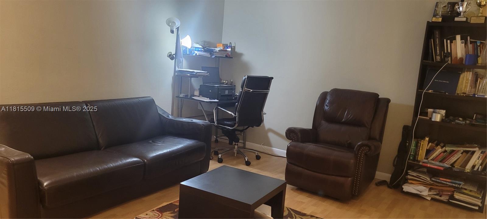 A living room features a brown leather sofa, a matching armchair, a desk, and a bookshelf — 1958 Monroe St # 107, Hollywood FL 33020, HOLLYWOOD, FL