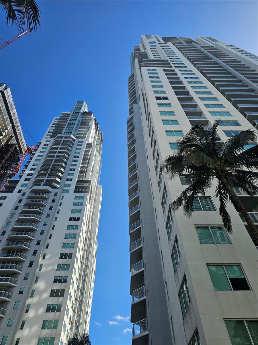 Low-angle view of two tall, modern residential high-rise buildings against a clear blue sky — 244 Biscayne Blvd # 908, Miami FL 33132, MIAMI, FL