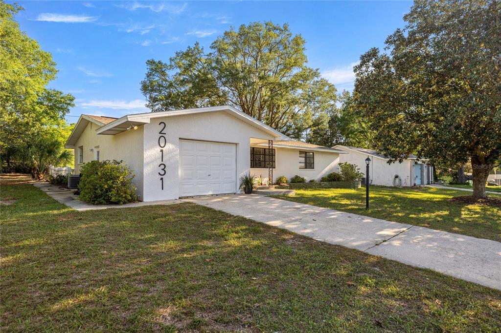 A single-story house with a white exterior, a one-car garage, and a concrete driveway — 20131 SW 83RD STREET, DUNNELLON, FL