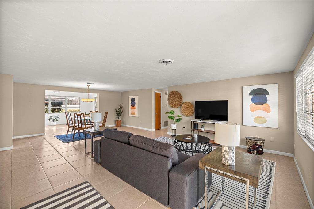 A living room with tile floors, a dark sofa, and an adjacent dining area — 20131 SW 83RD STREET, DUNNELLON, FL