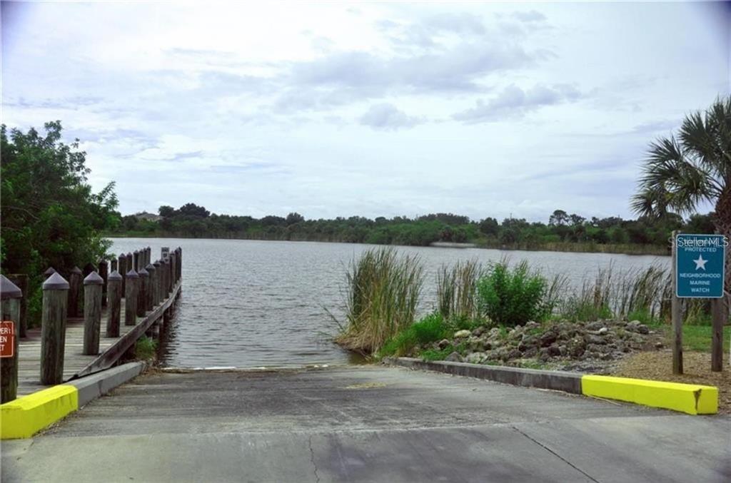 A concrete boat ramp leads into a lake next to a wooden dock — 14407 MORRISTOWN AVENUE, PORT CHARLOTTE, FL