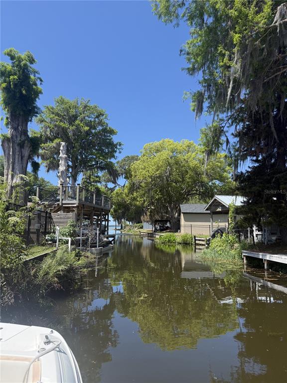 A view from a boat looking down a narrow canal lined with trees and houses — 11349 DAVISON LANE, TAVARES, FL
