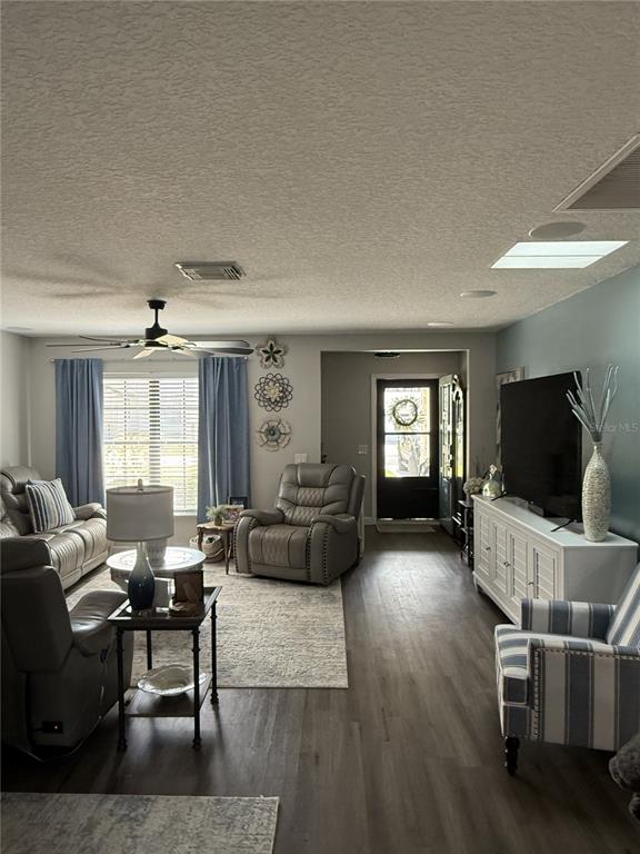 A living room features gray wood-look flooring, a ceiling fan, and a television on a console — 11349 DAVISON LANE, TAVARES, FL