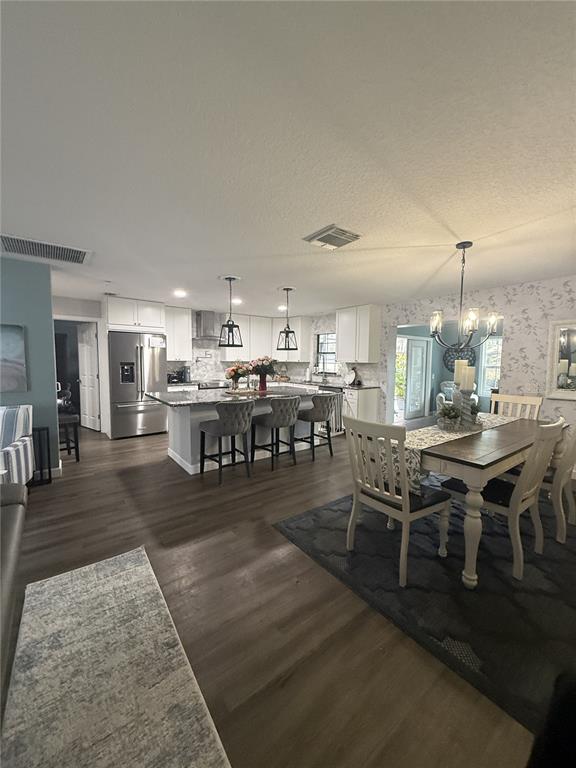 An open-concept kitchen and dining area features white cabinetry, a granite island, and wood flooring — 11349 DAVISON LANE, TAVARES, FL