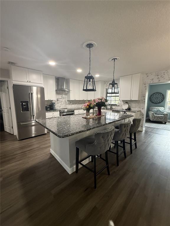 A kitchen features white cabinets, a granite-topped island with three gray stools, and wood flooring — 11349 DAVISON LANE, TAVARES, FL