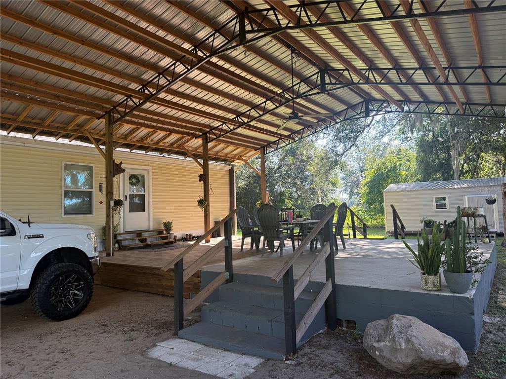 A large covered patio features a concrete deck, wooden stairs, and outdoor dining furniture — 4920 W KNIGHTS GRIFFIN ROAD, PLANT CITY, FL
