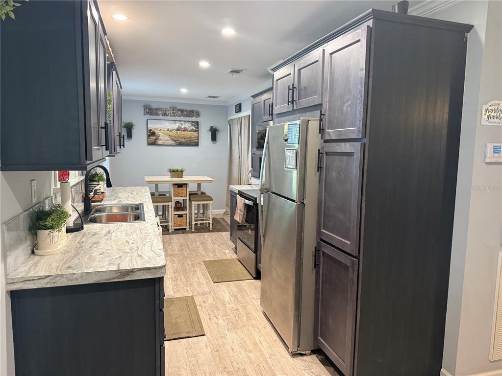 A kitchen features dark cabinets, stainless steel appliances, and a small dining area with stools — 4920 W KNIGHTS GRIFFIN ROAD, PLANT CITY, FL