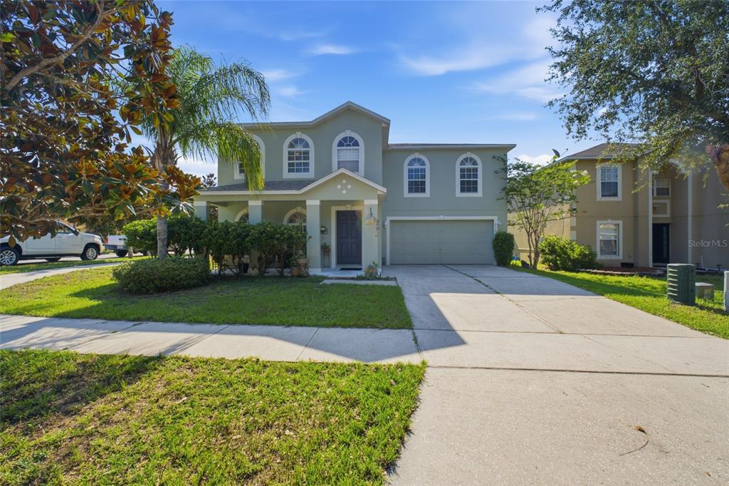 A two-story house with a light green exterior, a front porch, and a two-car garage — 516 CADIZ DRIVE, GROVELAND, FL