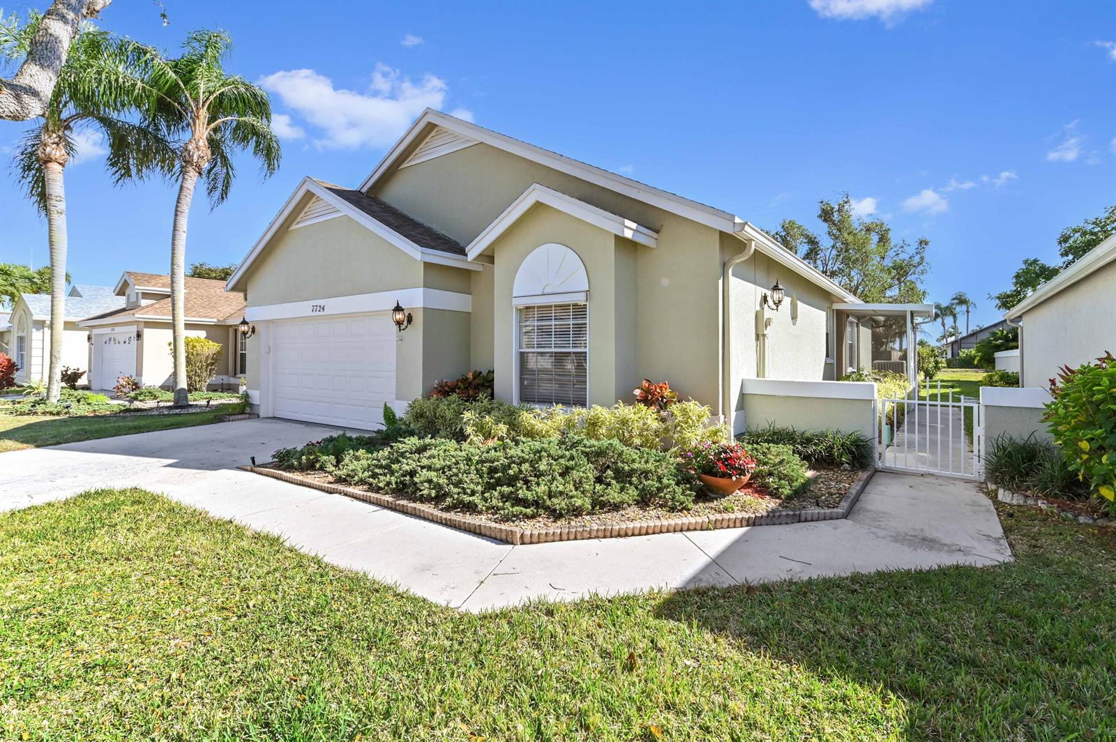 A single-story house with a beige stucco exterior, a two-car garage, and a landscaped yard — 7724 Mansfield Hollow Road, Delray Beach FL 33446, DELRAY BEACH, FL