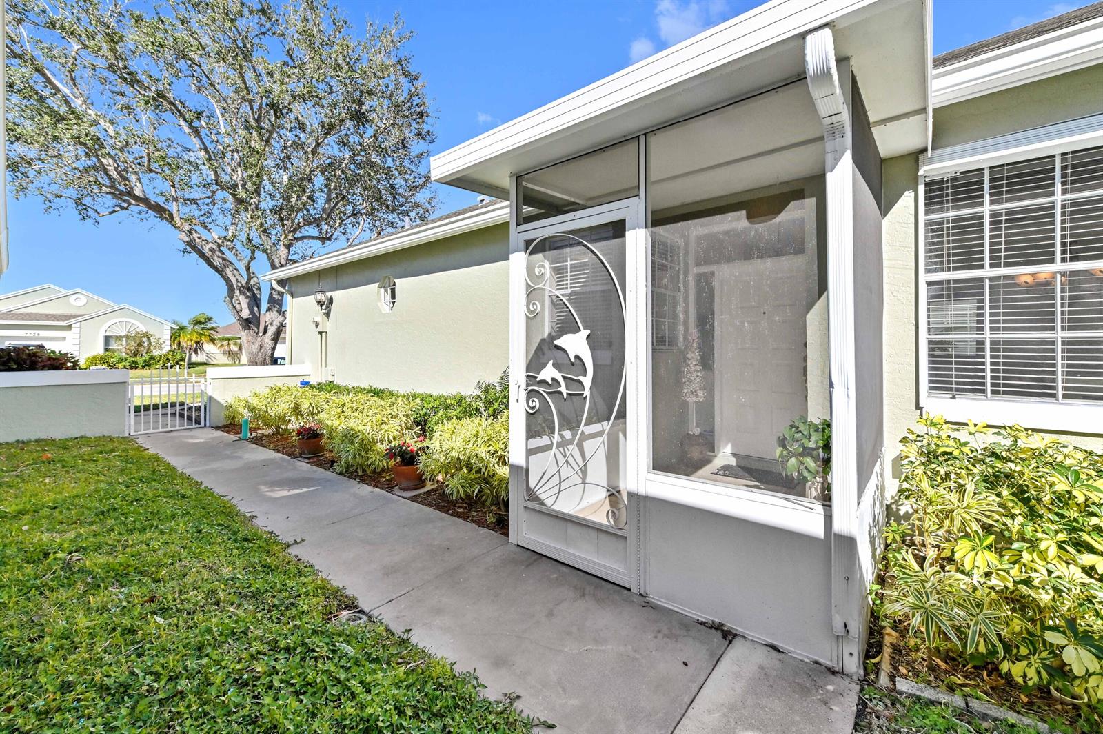 A concrete walkway leads to the screened front entryway of a light-colored house — 7724 Mansfield Hollow Road, Delray Beach FL 33446, DELRAY BEACH, FL
