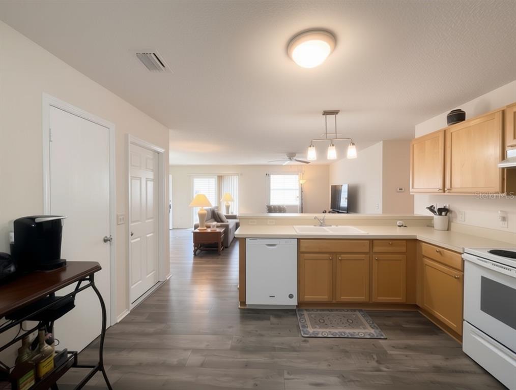 A kitchen with light wood cabinets, white appliances, and wood-look flooring — 16938 SE 94TH SUNNYBROOK CIRCLE, THE VILLAGES, FL