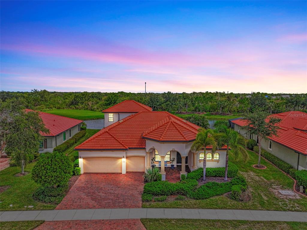 An aerial view of a single-story house with a red tile roof and brick driveway — 10908 BULLRUSH DRIVE, VENICE, FL
