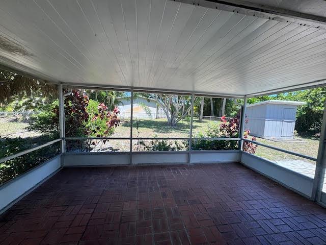 A screened-in porch with a brick floor overlooks a backyard with a small shed — 709 SE Alamanda Way, Stuart FL 34996, STUART, FL