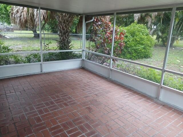 A screened-in porch with a red brick floor and views of a grassy backyard — 709 SE Alamanda Way, Stuart FL 34996, STUART, FL