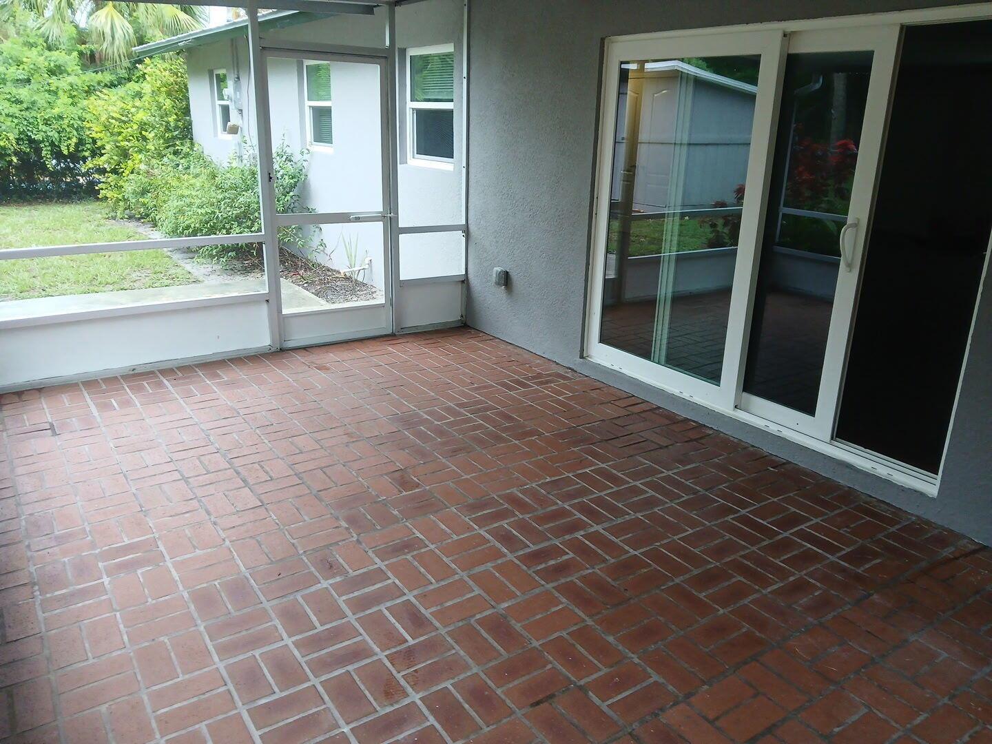 A covered patio features red brick flooring, a screen enclosure, and sliding glass doors — 709 SE Alamanda Way, Stuart FL 34996, STUART, FL