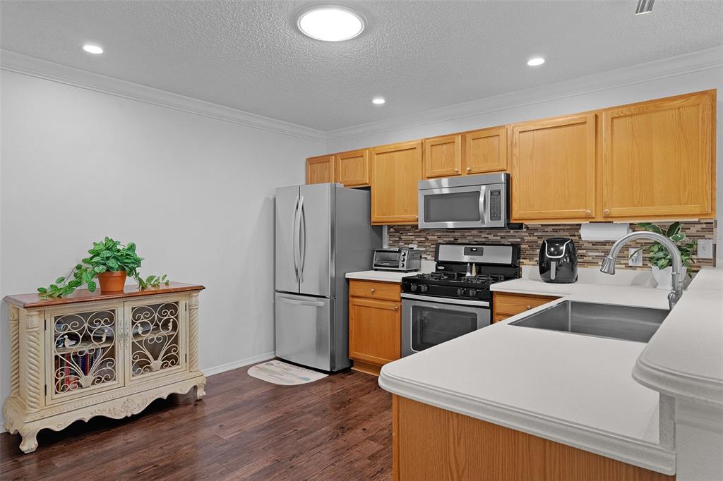 A kitchen features wood cabinets, stainless steel appliances, and a white countertop island — 17431 SE 93RD RETFORD TERRACE, THE VILLAGES, FL