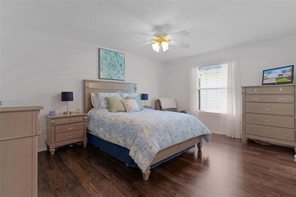 A bedroom features a bed with floral bedding, a ceiling fan, and wood-look flooring — 17431 SE 93RD RETFORD TERRACE, THE VILLAGES, FL