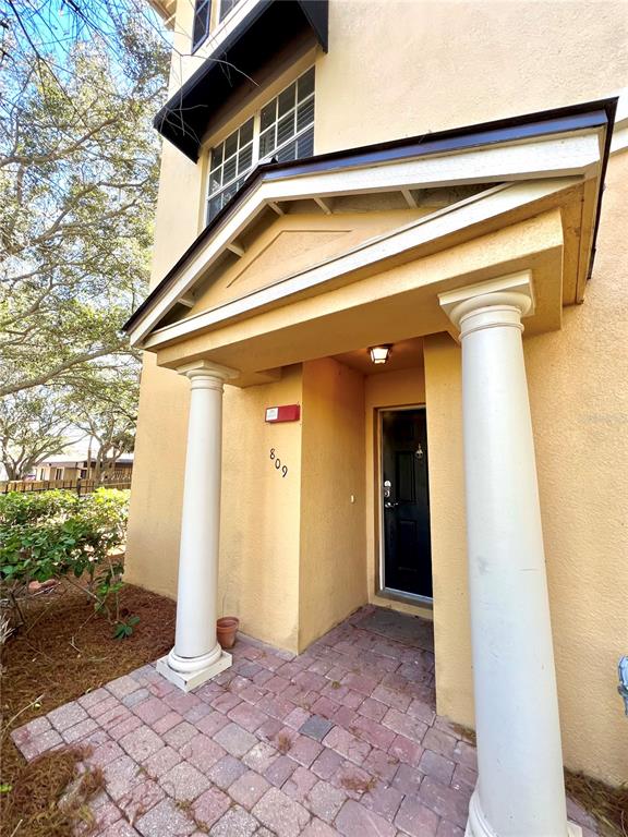 The exterior entrance features a covered porch with two white columns and a brick walkway — 809 HARBOR OAK LANE, CLEARWATER, FL