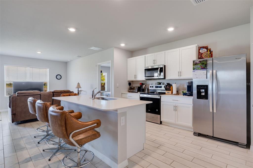 A kitchen with white cabinets, stainless steel appliances, and a central island with bar seating — 2608 TABLE CORAL TRAIL, NORTH FORT MYERS, FL