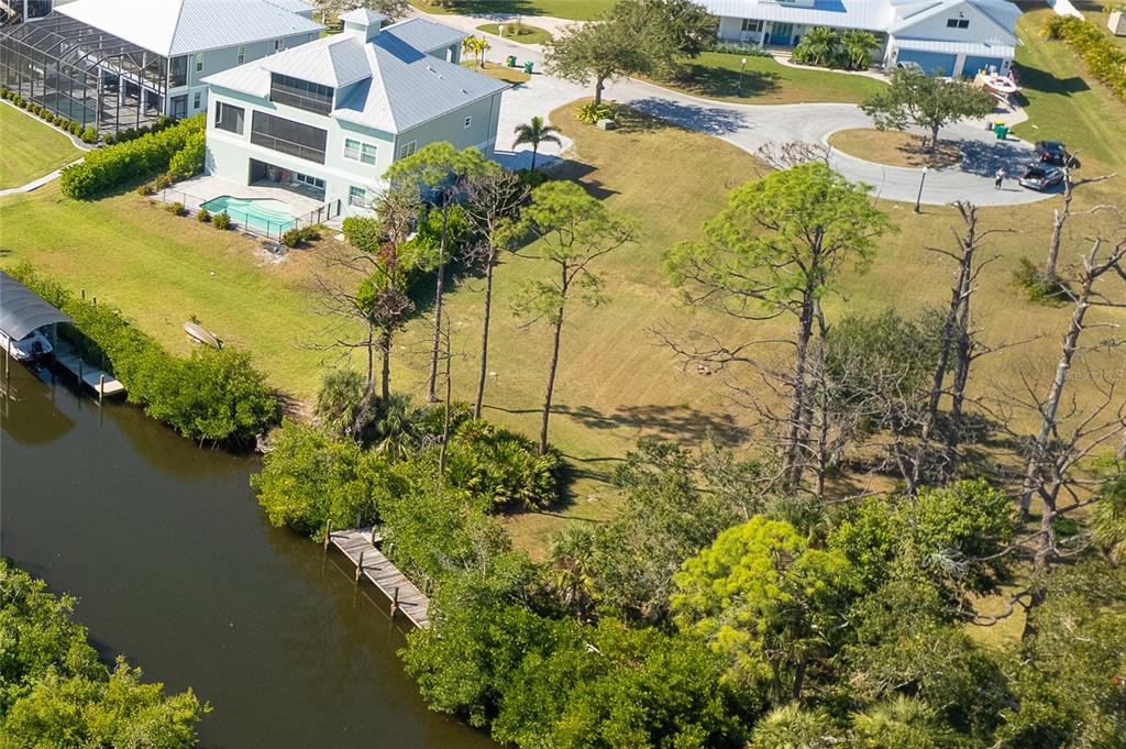 An aerial view shows a waterfront property with a house, pool, dock, and wooded lot — 8089 WEYERS COURT, ENGLEWOOD, FL