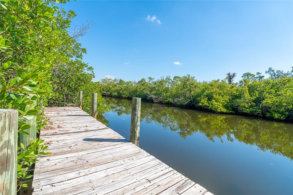 A wooden dock extends over a calm canal surrounded by lush green mangrove trees — 8089 WEYERS COURT, ENGLEWOOD, FL