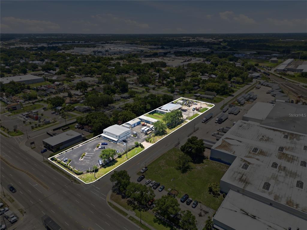 An aerial view shows a commercial property with a parking lot and several warehouse buildings — 513 ARIANA AVENUE, AUBURNDALE, FL