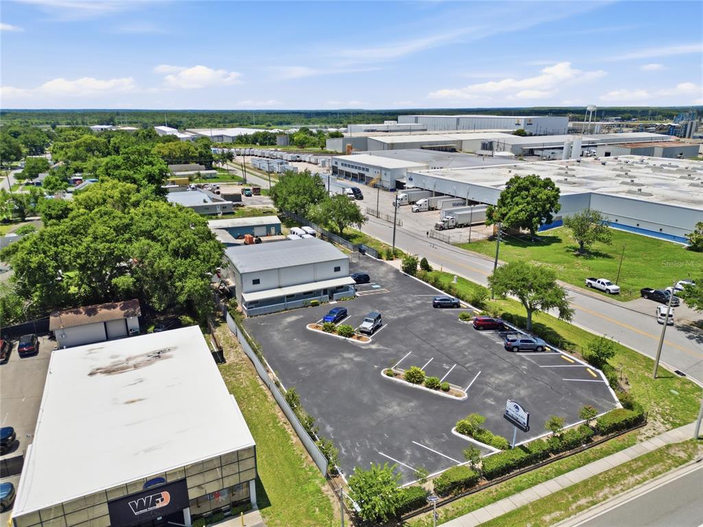 An aerial view shows a commercial building with a parking lot and surrounding industrial facilities — 513 ARIANA AVENUE, AUBURNDALE, FL