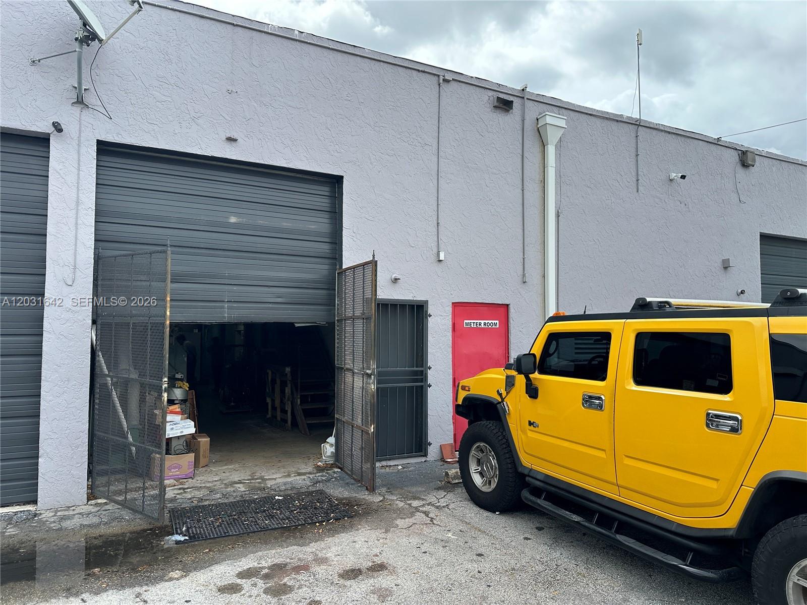 A yellow Hummer is parked outside a commercial building with a roll-up door and meter room — 3960 W 16th Ave # 205, Hialeah FL 33012, HIALEAH, FL