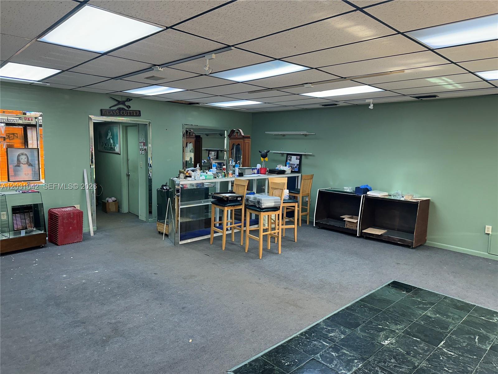 A commercial space features green walls, a drop ceiling, gray carpeting, and a service counter — 3960 W 16th Ave # 205, Hialeah FL 33012, HIALEAH, FL