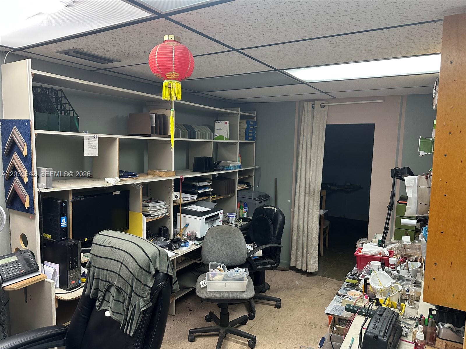 A cluttered office space features shelving units, multiple desks, office chairs, and a hanging lantern — 3960 W 16th Ave # 205, Hialeah FL 33012, HIALEAH, FL