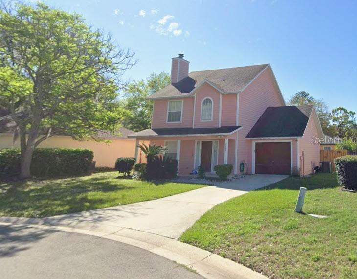 A two-story pink house with a dark roof and a single-car garage sits on a lawn — 2509 NW 37TH PLACE, GAINESVILLE, FL