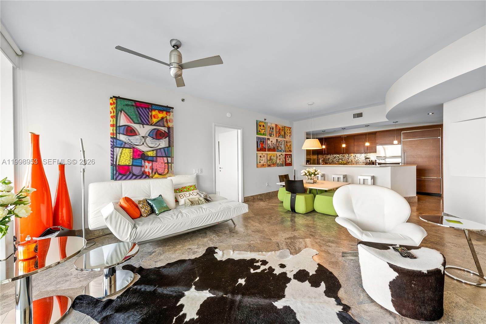 This open-concept living and dining area features marble floors, modern furniture, and colorful wall art — 450 Alton Rd # 704, Miami Beach FL 33139, MIAMI BEACH, FL