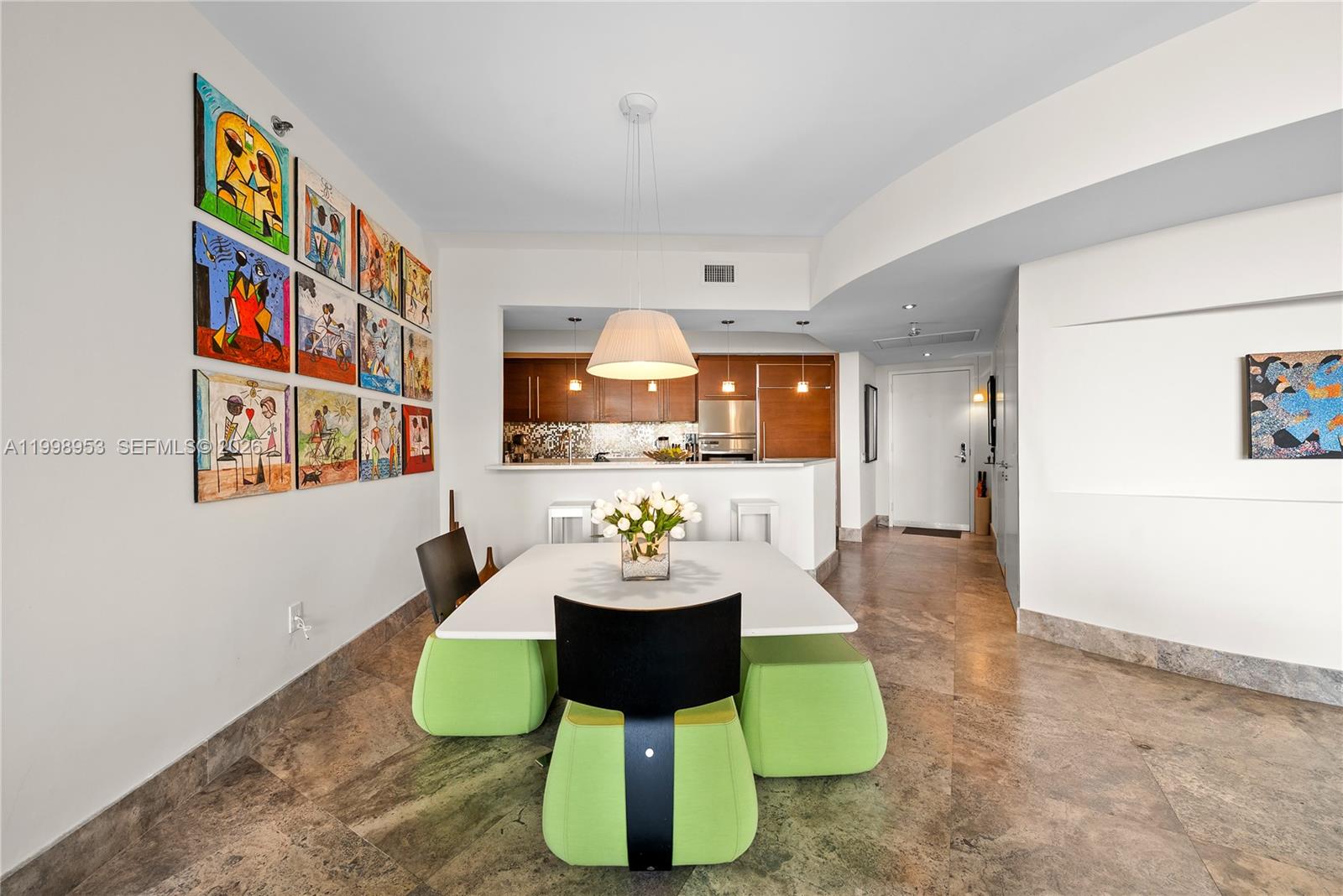 A dining area features a white table, green stools, and a gallery wall of art — 450 Alton Rd # 704, Miami Beach FL 33139, MIAMI BEACH, FL
