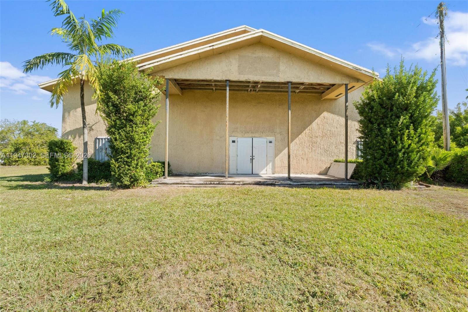 The exterior of a beige building features a covered porch with metal support columns — 21571 SW 110th Ave, Miami FL 33189, MIAMI, FL