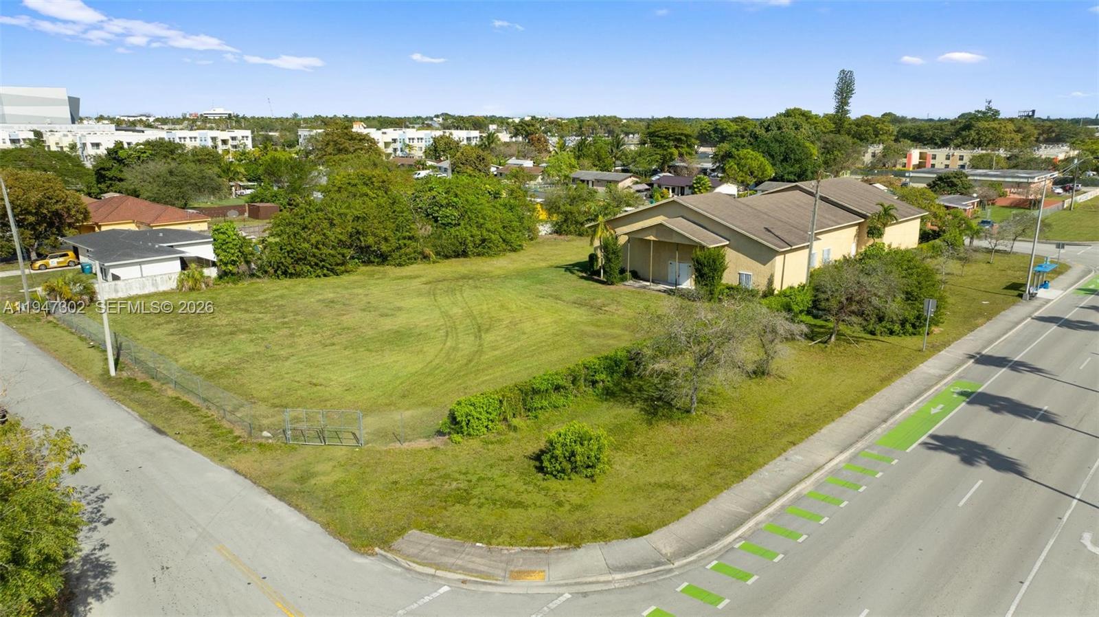 An aerial view shows a vacant grassy lot next to a tan building — 21571 SW 110th Ave, Miami FL 33189, MIAMI, FL