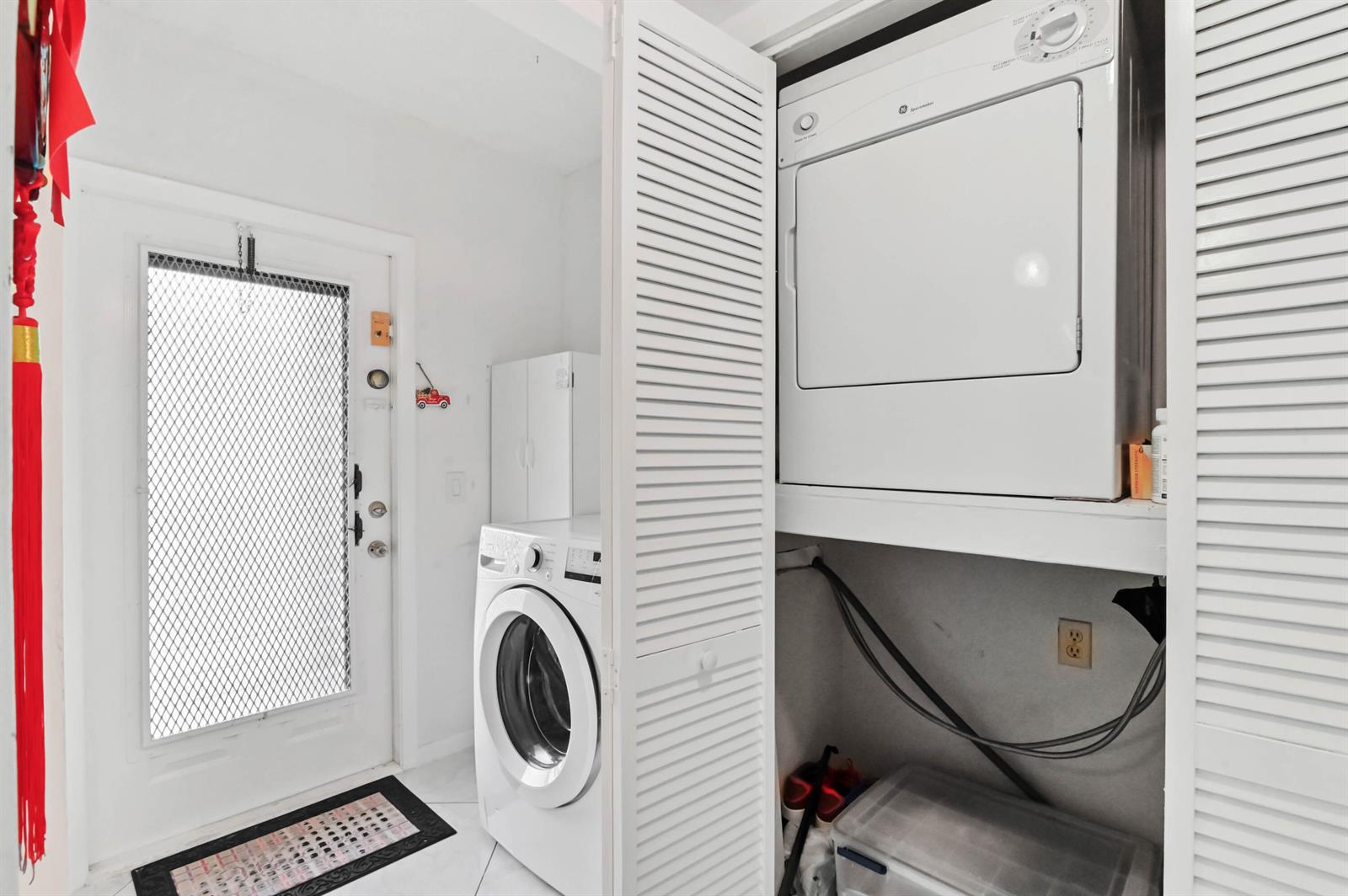 A laundry closet with a stacked dryer and a front-loading washer sits near an exterior door — 2860 SW 22nd Avenue # 4040, Delray Beach FL 33445, DELRAY BEACH, FL