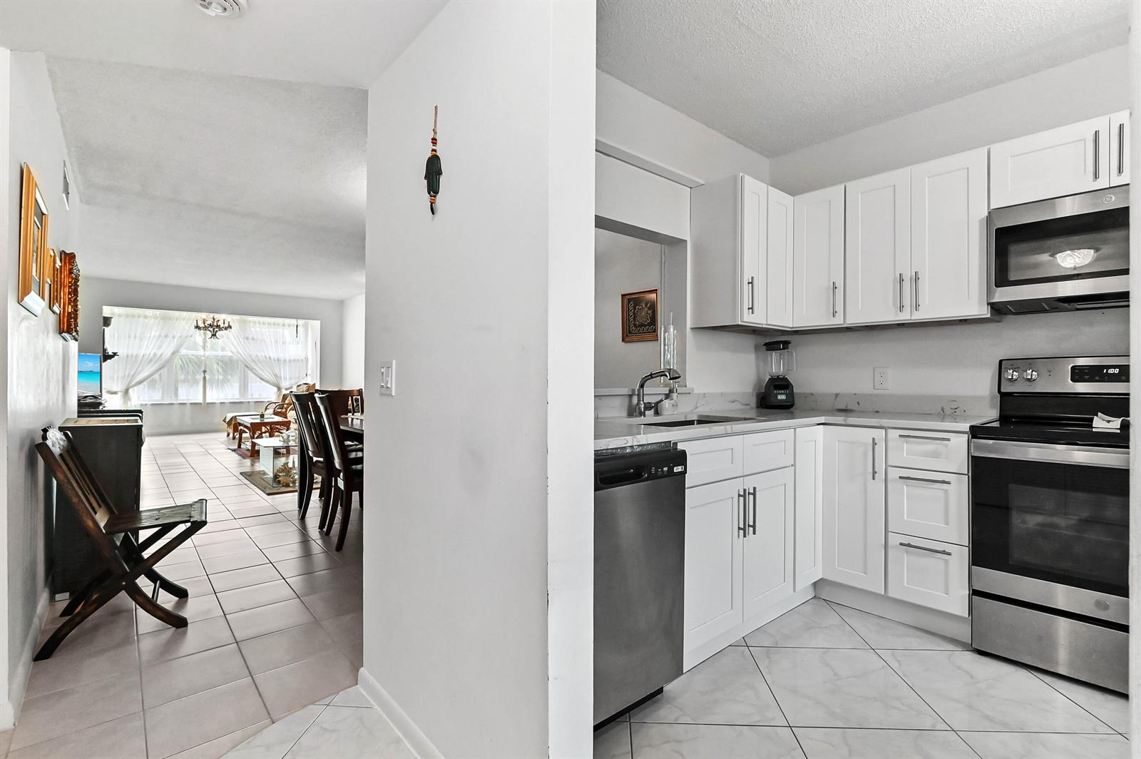 A white kitchen with stainless steel appliances opens into a dining and living area — 2860 SW 22nd Avenue # 4040, Delray Beach FL 33445, DELRAY BEACH, FL