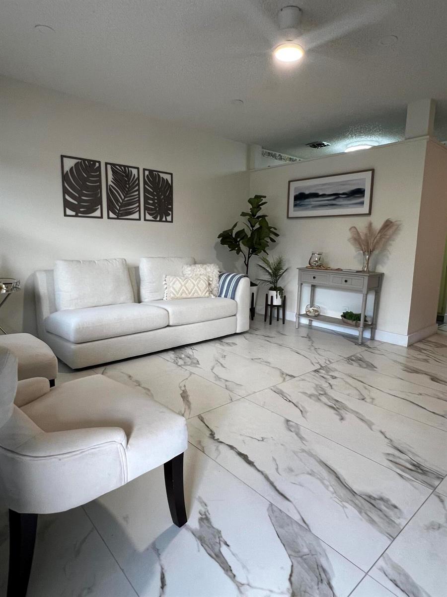 A living room features a white sofa, two armchairs, and large white marble-patterned floor tiles — 900 SW 10th Terrace # S20, Hallandale Beach FL 33009, HALLANDALE BEACH, FL