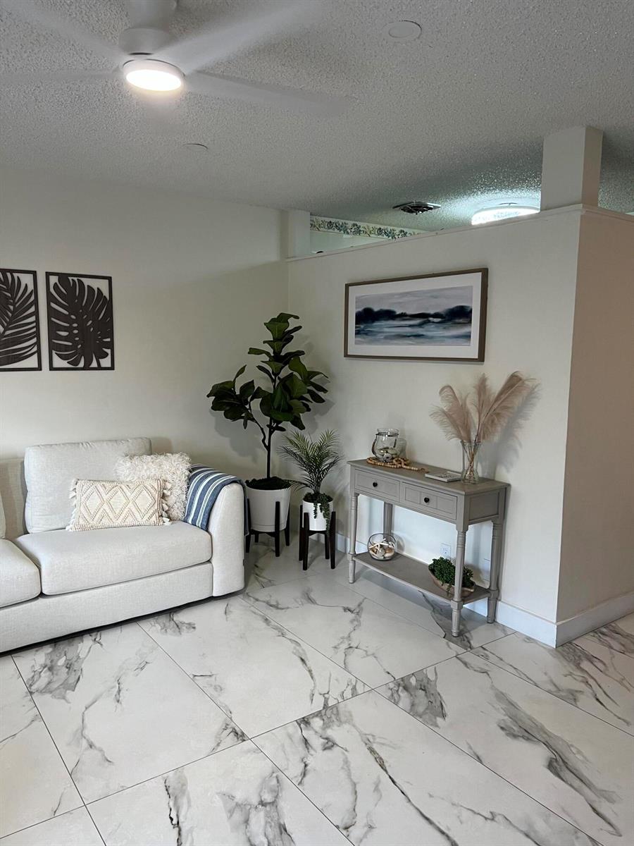 A living room features a white sofa, a console table, potted plants, and marble-look flooring — 900 SW 10th Terrace # S20, Hallandale Beach FL 33009, HALLANDALE BEACH, FL